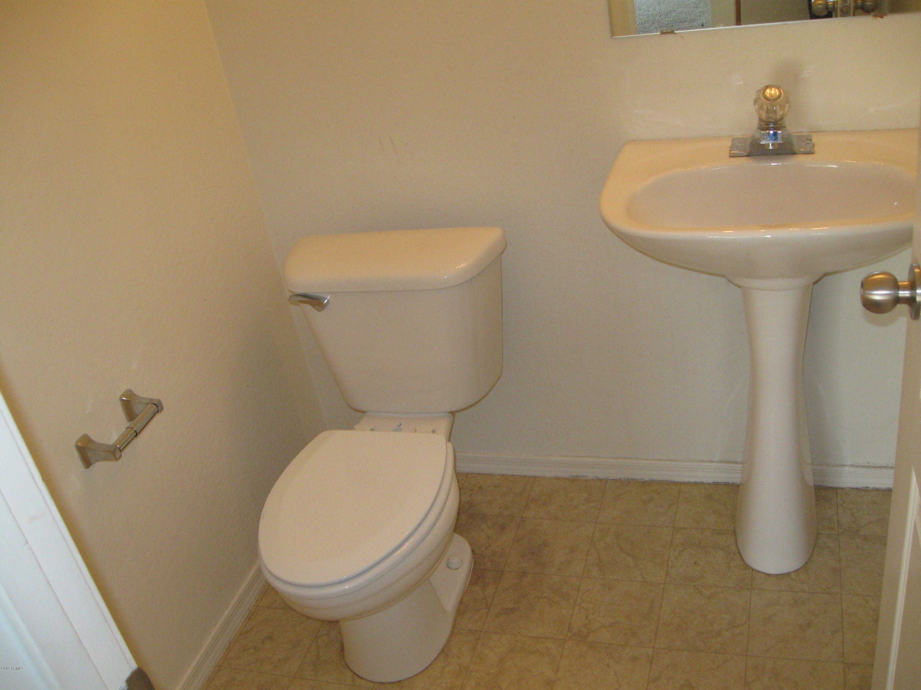 8746 West Heber Road Tolleson, AZ 85353 - Photo 11 of 36 a white toilet sitting next to a bathroom sink