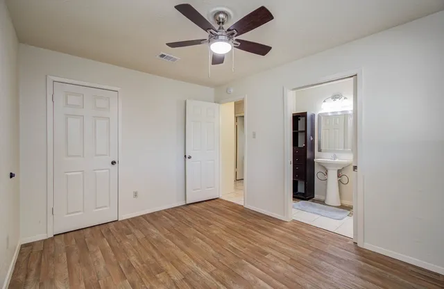 a view of empty room with wooden floor and ceiling fan