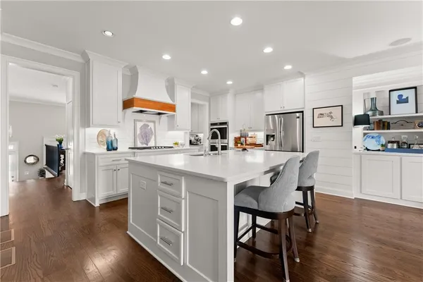 a kitchen with stainless steel appliances granite countertop a stove a sink a refrigerator cabinets and a dining table with wooden floor
