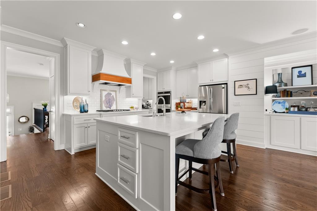 3206 Ridge Towne Place Duluth, GA 30096 - Photo 1 of 42 a kitchen with stainless steel appliances granite countertop a stove a sink a refrigerator cabinets and a dining table with wooden floor