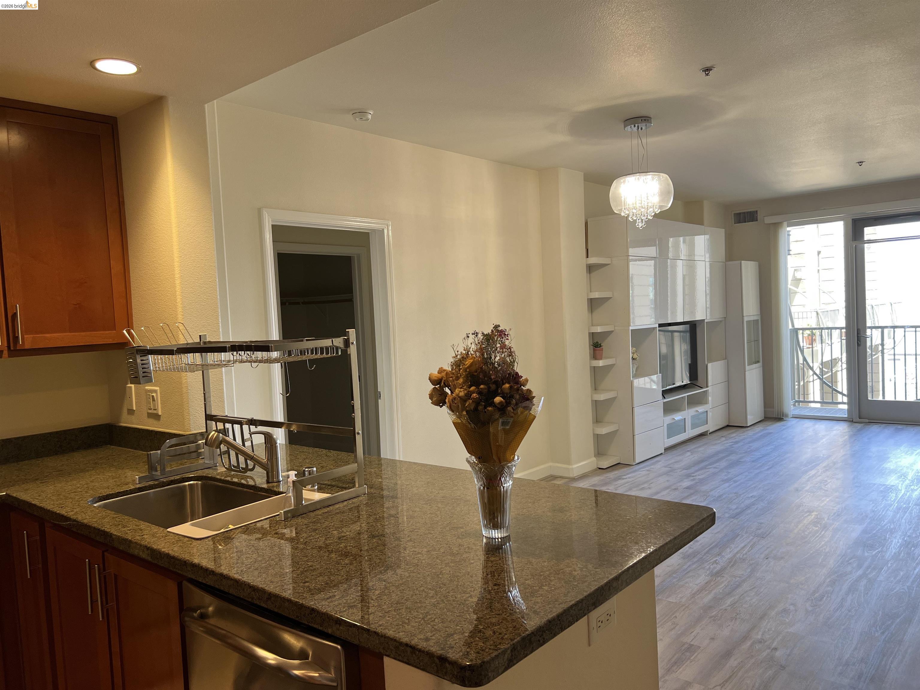 423 7th Street, Unit 313 Oakland, CA 94607 - Photo 5 of 11 Kitchen island with stone-finish countertop, stainless steel sink, and dishwasher