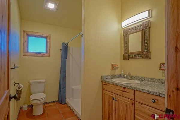 a bathroom with a granite countertop toilet sink and mirror