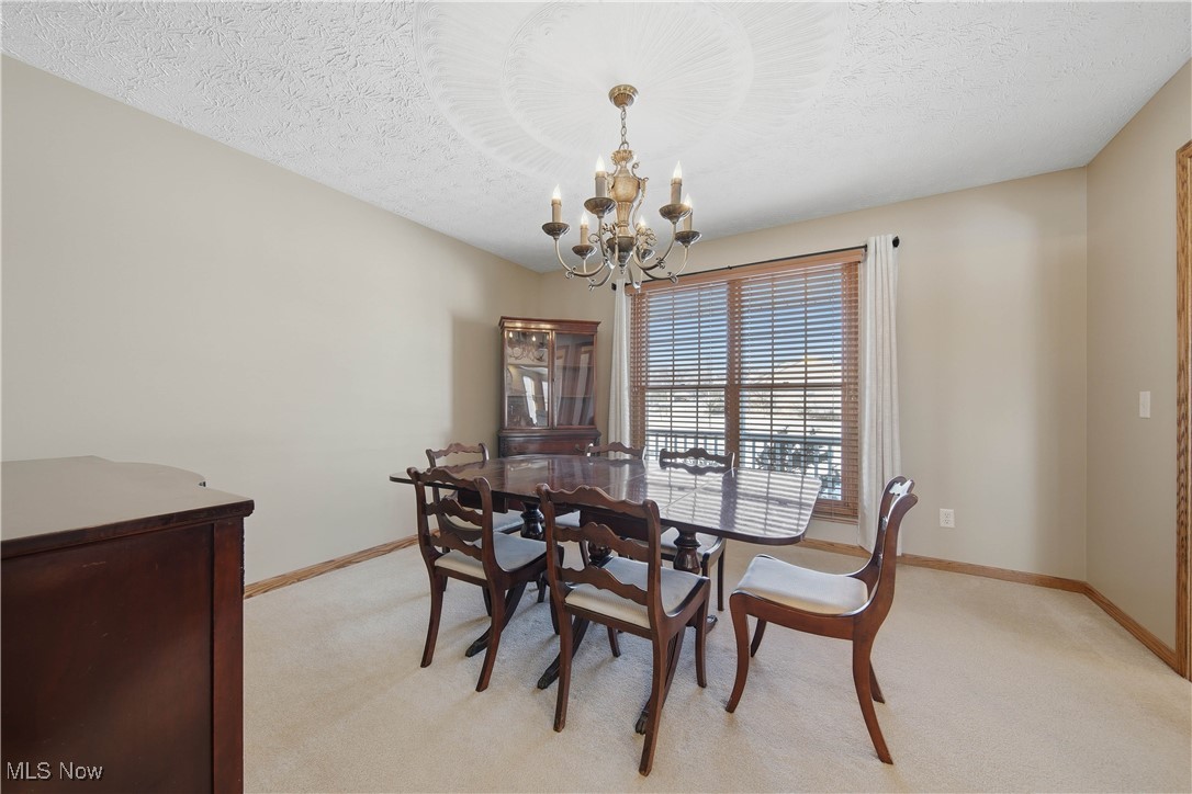 2132 Summerchase Road Northeast Canton, OH 44721 - Photo 7 of 49 Dining room with a textured ceiling, light colored carpet, and a chandelier