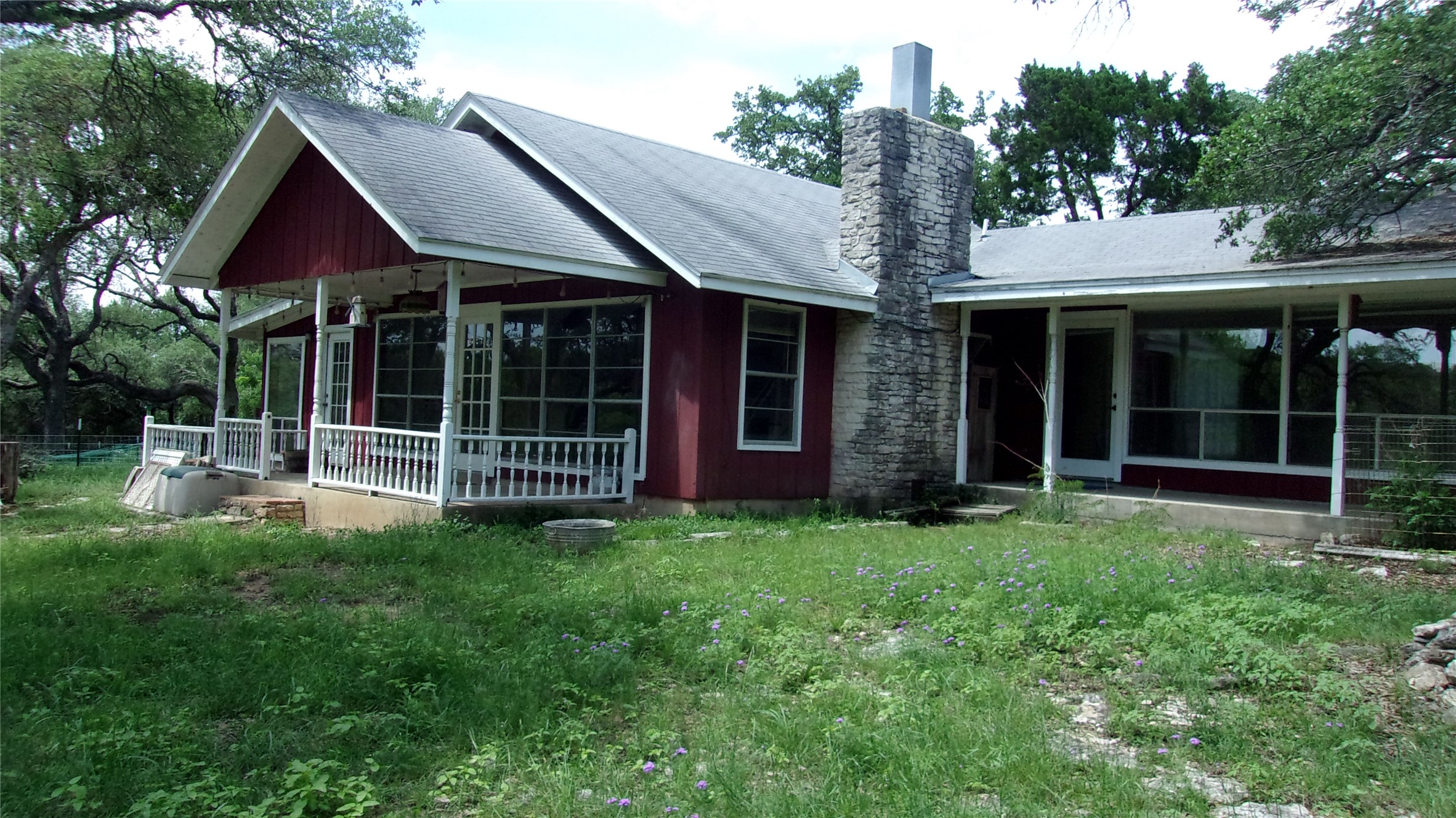 702 Cottonwood Creek Road Dripping Springs, TX 78620 - Photo 2 of 31 Red exterior with a stone chimney and a covered front porch featuring white railings