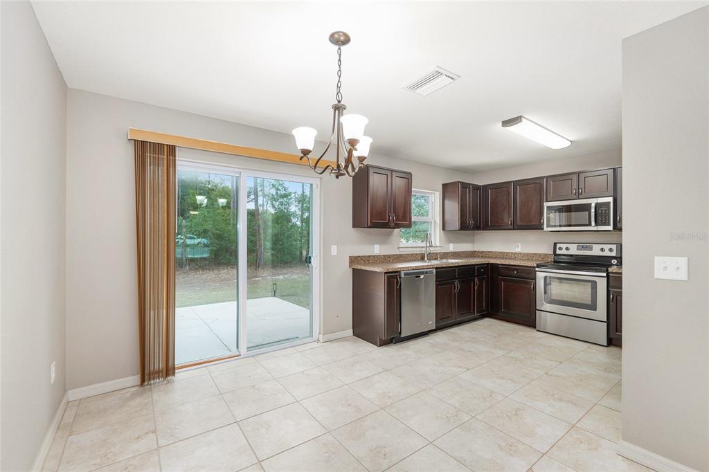 2 Hemlock Loop Drive Ocala, FL 34472 - Photo 8 of 28 a kitchen with stainless steel appliances kitchen island granite countertop a stove top oven a sink dishwasher a dining table and chairs