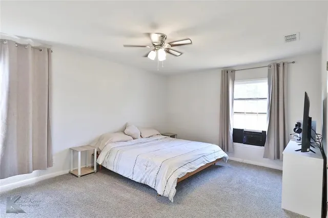a bedroom with a bed and a flat tv screen on the dresser