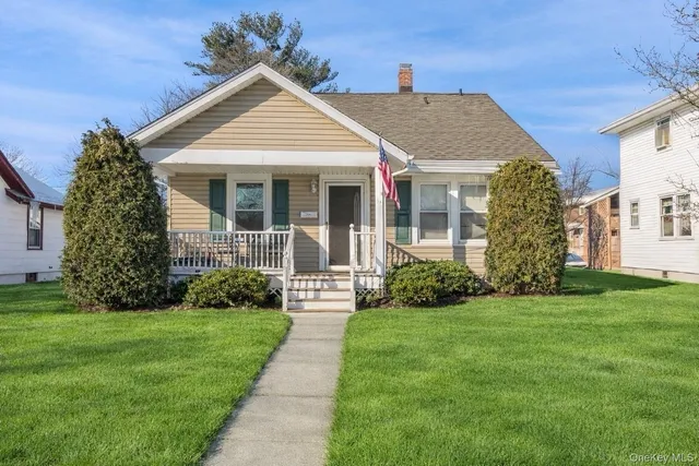 a front view of a house with a yard and potted plants