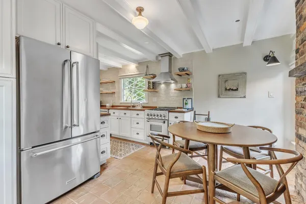 a kitchen with stainless steel appliances granite countertop a dining table chairs refrigerator and cabinets