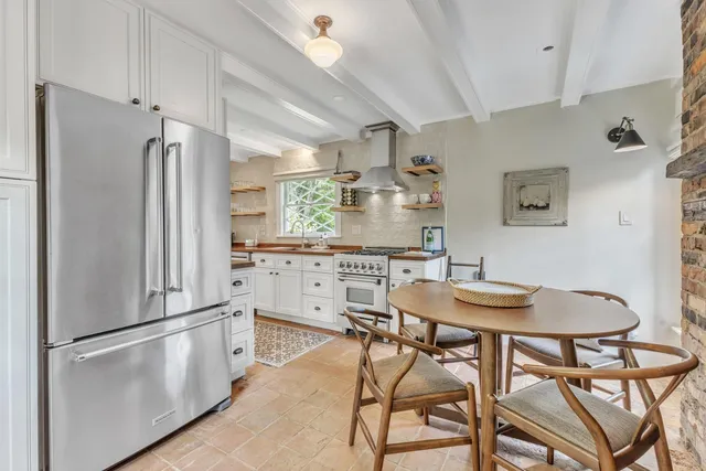 a kitchen with stainless steel appliances granite countertop a dining table chairs refrigerator and cabinets