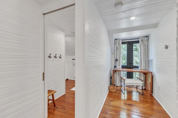 a view of a hallway with wooden floor and a bathroom