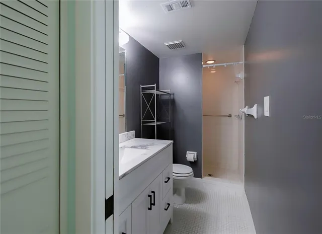 a bathroom with a double vanity sink a toilet and shower