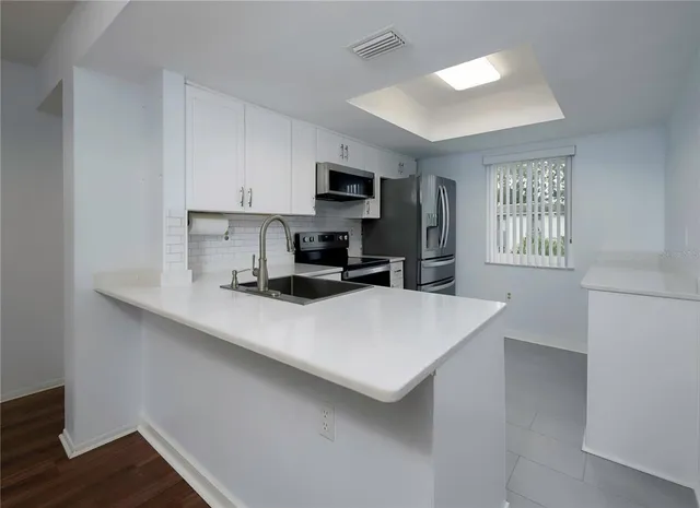 a kitchen with stainless steel appliances a sink a stove a refrigerator cabinets and a window