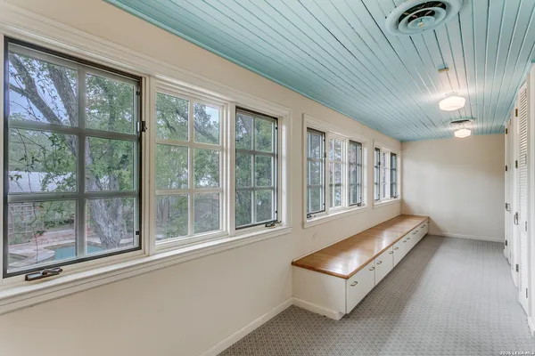 an empty room with wooden floor chandelier and windows