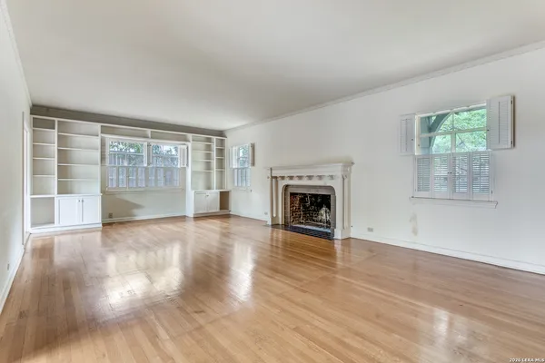 a view of empty room with wooden floor and fireplace