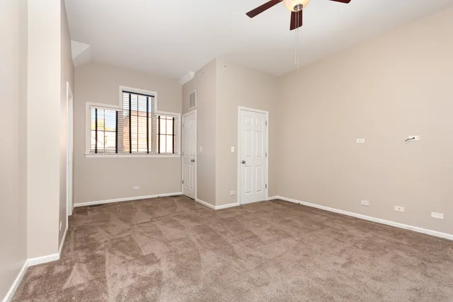 an empty room with chandelier fan and windows