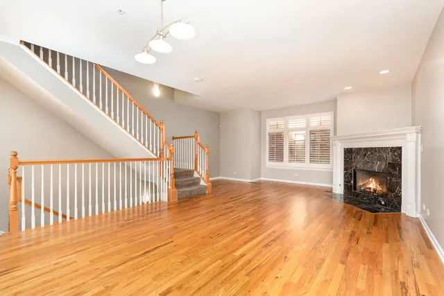 a view of an empty room with wooden floor fireplace and a window