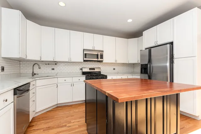 a kitchen with stainless steel appliances granite countertop a refrigerator sink stove microwave and cabinets