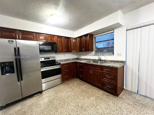 a kitchen with granite countertop wooden cabinets a refrigerator and a sink