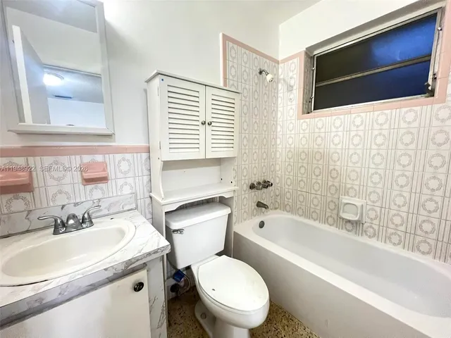a bathroom with a sink toilet a mirror and bathtub