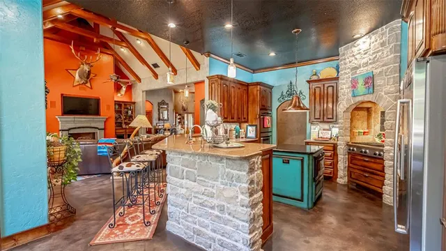 a view of a kitchen with stainless steel appliances kitchen island granite countertop a refrigerator and a stove
