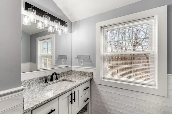 a bathroom with a granite countertop sink and a large mirror