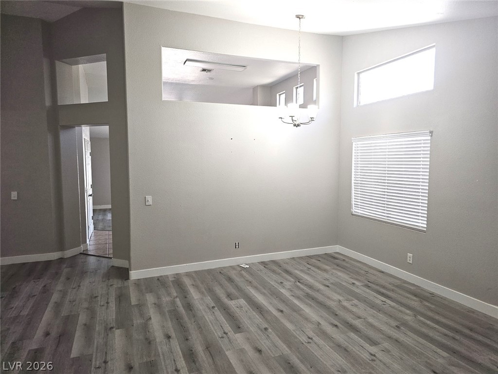 1418 Reebok Terrace Henderson, NV 89014 - Photo 11 of 38 An airy living space features a modern chandelier and light-filtering blinds, offering abundant natural illumination.