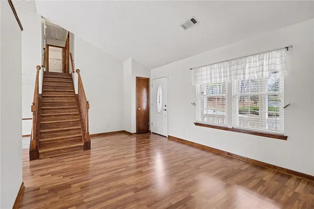 a view of an empty room with wooden floor and stairs