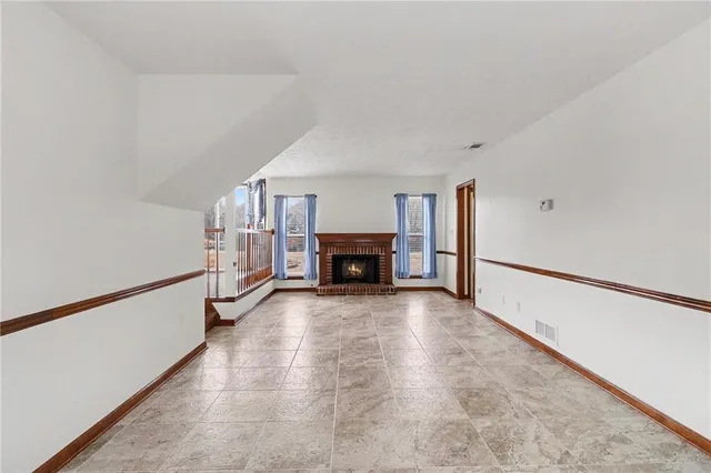 a view of an empty room with stairs and a window