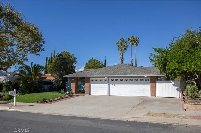 a view of a house with a small yard and a large tree
