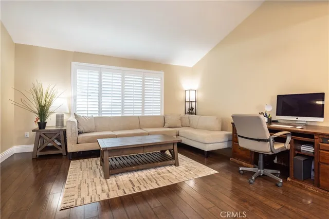 a living room with a table chairs and a dining table with wooden floor