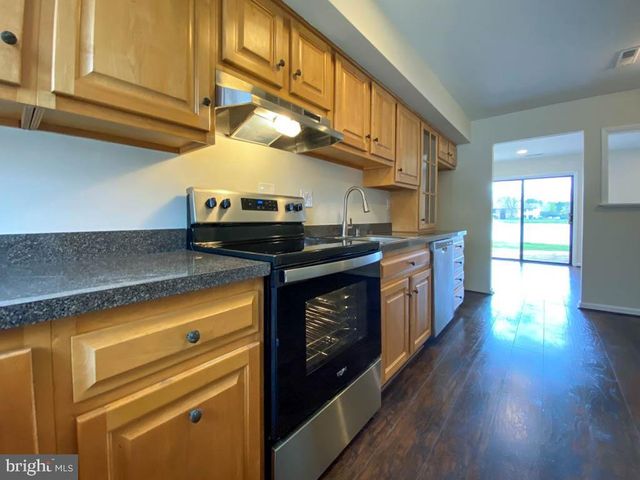 a kitchen with stainless steel appliances granite countertop a sink a stove and a wooden floors
