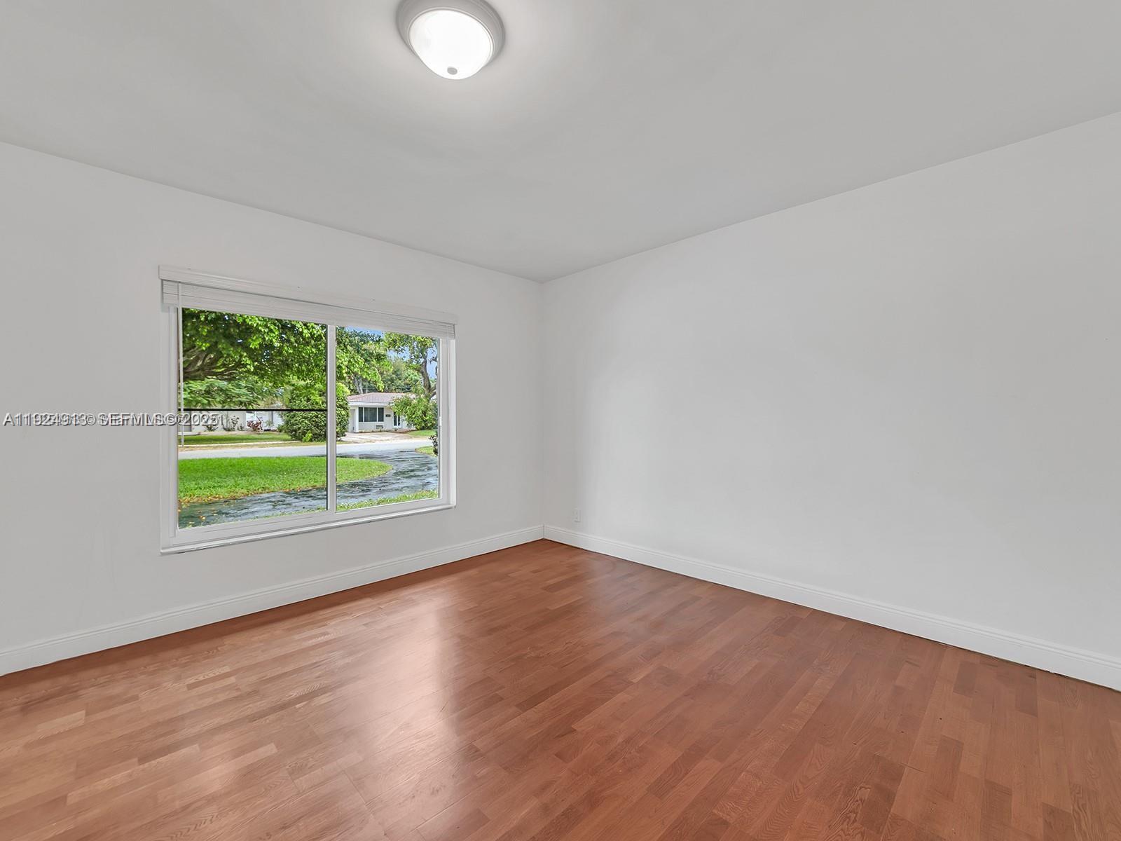 2620 Northeast 19th Street Pompano Beach, FL 33062 - Photo 23 of 42 a view of an empty room with wooden floor and a window