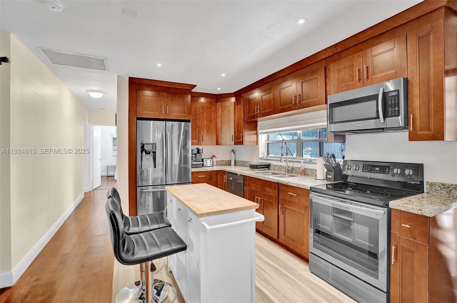 2620 Northeast 19th Street Pompano Beach, FL 33062 - Photo 9 of 42 a kitchen with stainless steel appliances granite countertop a refrigerator a sink dishwasher a stove and white cabinets with wooden floor