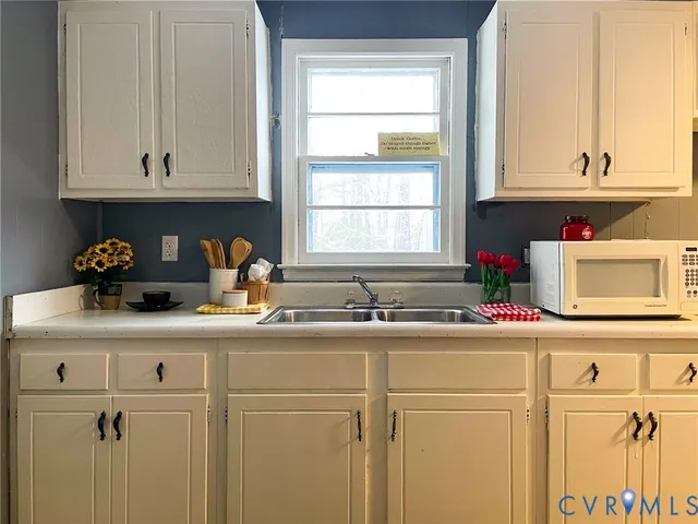 a kitchen with white cabinets and sink