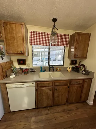 a view of a kitchen with a sink stainless steel appliances wooden floor and a window