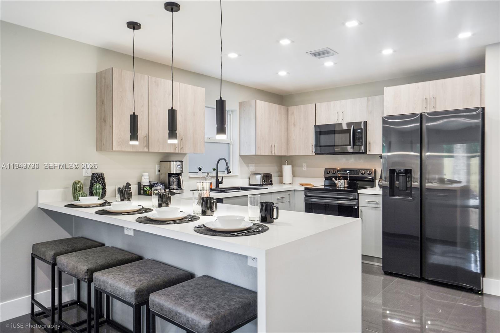 1035 Northwest 48th Street Miami, FL 33127 - Photo 2 of 29 a kitchen with a refrigerator a stove a sink and chairs