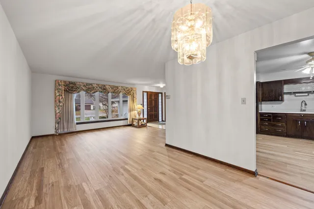 an empty room with wooden floor cabinet and windows