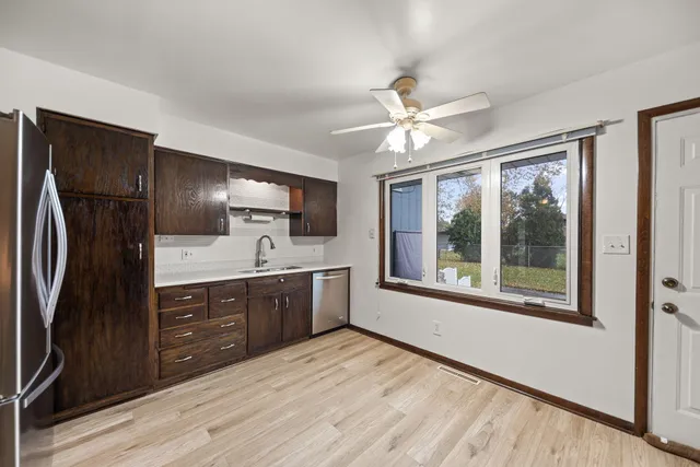 a kitchen with stainless steel appliances granite countertop a refrigerator a sink dishwasher a dining table and with fireplace