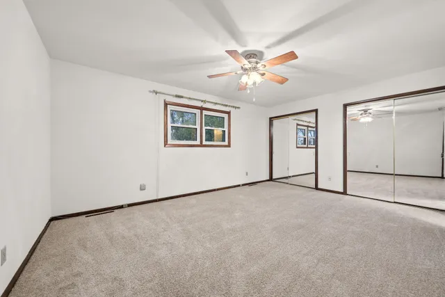 an empty room with windows and ceiling fan