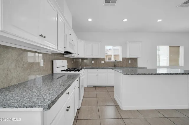 a large kitchen with granite countertop a sink a counter top space and cabinets