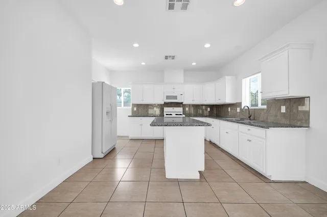 a view of an empty room with wooden floor and a ceiling fan