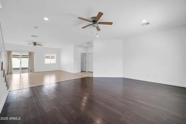 an empty room with wooden floor and ceiling fan