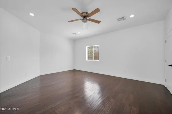 a view of empty room with wooden floor and fan