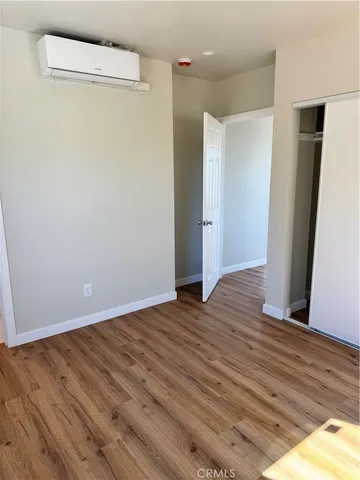 a view of an empty room with wooden floor and a bathroom