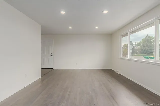 an empty room with wooden floor and windows