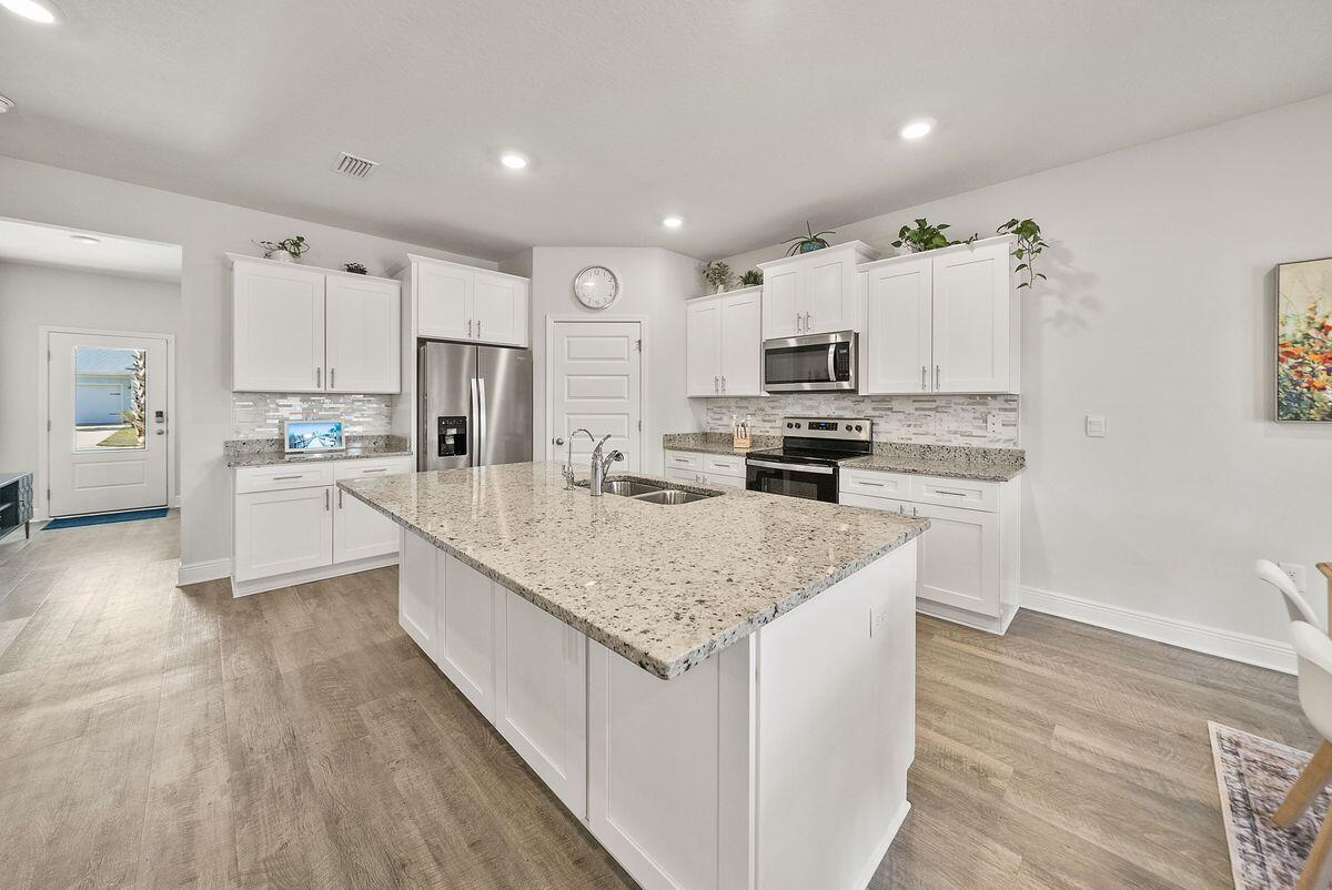 774 Backwater Road Port St. Joe, FL 32456 - Photo 12 of 65 a kitchen with kitchen island granite countertop a sink refrigerator and microwave