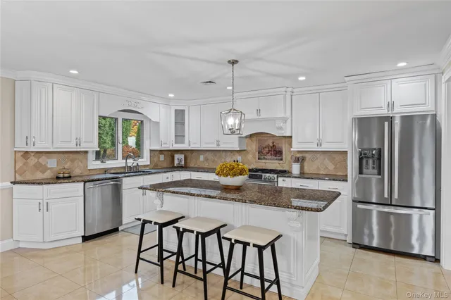 a kitchen with stainless steel appliances granite countertop a sink a stove a refrigerator cabinets and chairs