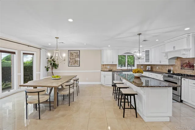 a kitchen with kitchen island a dining table chairs stainless steel appliances and cabinets