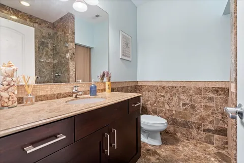 a bathroom with a granite countertop sink a toilet and a mirror