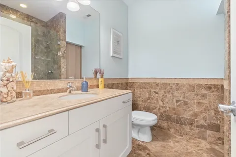 a bathroom with a granite countertop sink a toilet and a mirror